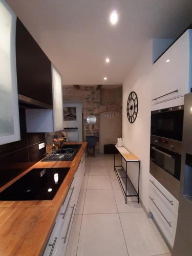une cuisine avec un comptoir et une horloge au mur dans l'établissement Appartement grand confort au cœur de Millau, à Millau
