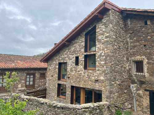 an old stone house with a stone wall at La era de Somaniezo in Luriezo