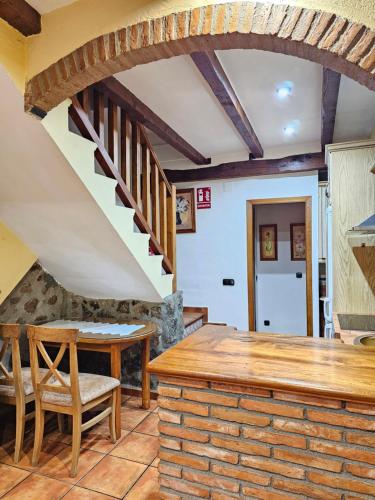 a kitchen with a staircase and a table and chairs at Casa Rural El Campanario in Jerte