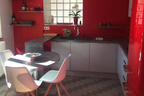 une cuisine avec des murs rouges et une table et des chaises dans l'établissement Cosy Chalet - Centre village, au calme, à Vallouise
