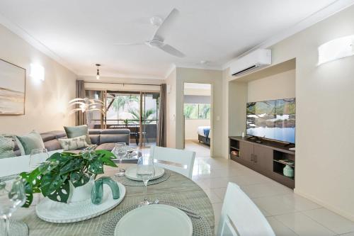 a living room with a dining table and a couch at Palmview Heights - 9 Pools BBQ & Gym in Westcourt