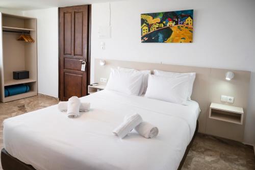 a bedroom with a large white bed with towels on it at Argo Rooms-Papadakis in Kissamos