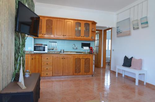 a kitchen with wooden cabinets and a flat screen tv at Villa Vargas Paraiso in Carrizal