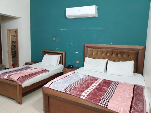 a bedroom with two beds and a blue wall at New Era Guest House And Hotel in Multan