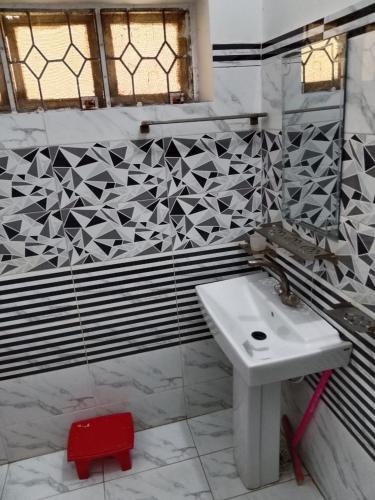 a bathroom with a white sink and a tile wall at New Era Guest House And Hotel in Multan