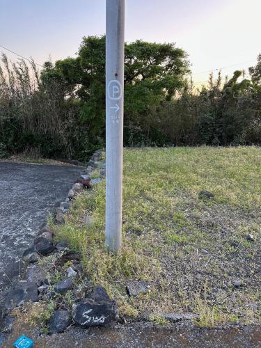 a pole in the grass next to a road at suo 椿の島の宿 in Oshima