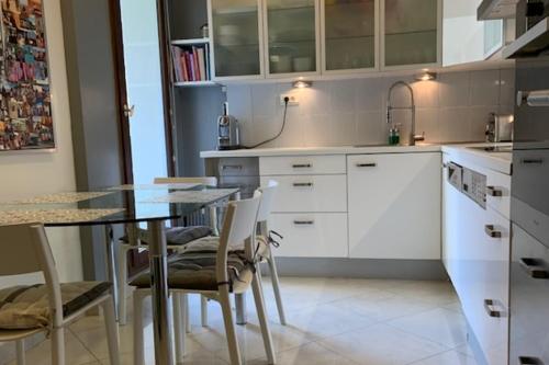 une cuisine avec des armoires blanches et une table et des chaises dans l'établissement Island of calm of 90 m2 at the gates of Paris, à Puteaux