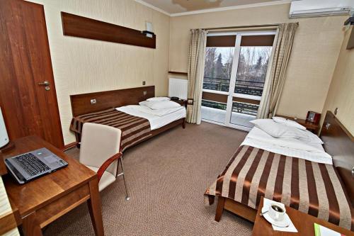 a hotel room with two beds and a desk with a laptop at Hotel Soccer Sport in Radomsko