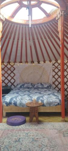 un lit dans une yourte avec une table dedans dans l'établissement La yourte Serenity des Volcans, à Saint-Saturnin