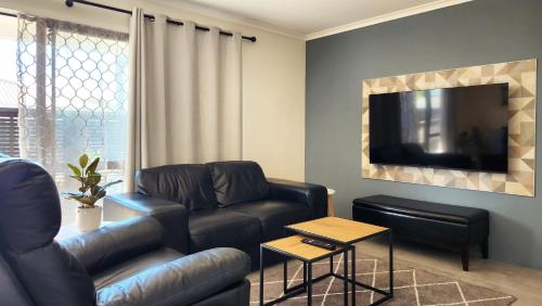 a living room with a leather couch and a tv at The Ranolf Residence in Rotorua
