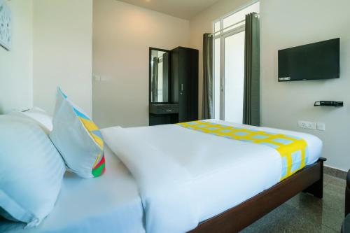a bedroom with a white bed with pillows and a television at Super Hotel O Elegant KINGS PARK RESIDENCY in Cochin