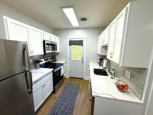 a kitchen with white cabinets and black appliances at Cozy Walk up King Bed fast WiFi in Wilmington