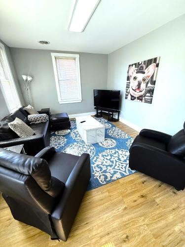 a living room with a black leather couch and a blue rug at Cozy Walk up King Bed fast WiFi in Wilmington