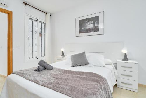 a white bedroom with two beds and a window at Apartamento B y G Nerja in Nerja