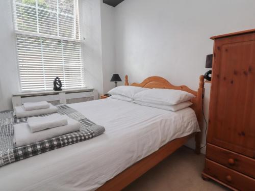 a bedroom with a bed with white sheets and a dresser at 2 Riverside Walk in Airton