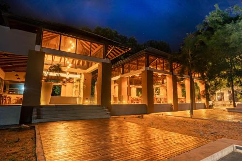 una casa grande con terraza de madera por la noche en LUXTORI Arugambay - In-house guests are entitled to a 10 percent off at Cilantro Restaurant, Bloom Cafe, and Zeste Bar Lounge, en Arugam Bay