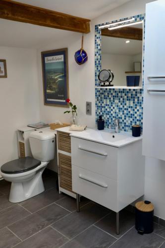 une salle de bain avec toilettes, lavabo et miroir dans l'établissement Grains de Sable, à Barneville-Carteret