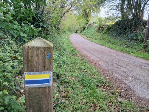 a sign on a wooden post on a dirt road at Chambre paisible avec jardin à la campagne en Finistère sud in Scaër