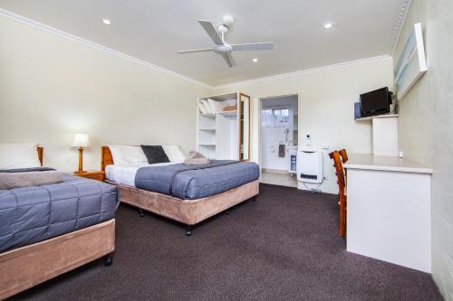 a hotel room with two beds and a television at Wintersun Gardens Motel in Bicheno