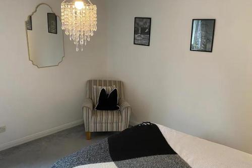 a bedroom with a chandelier and a chair with a black cat in it at 2 Bed-Sleeps 4-Sea View-Pet Friendly-Parking in Llanelli