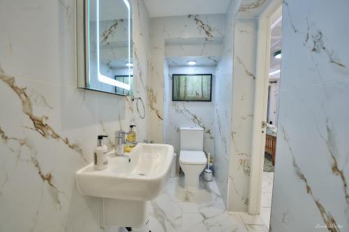 a white bathroom with a sink and a toilet at Luxury Studio in Wembley in Wembley