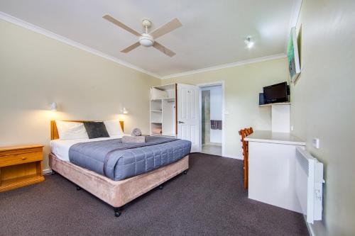 a bedroom with a bed and a ceiling fan at Wintersun Gardens Motel in Bicheno