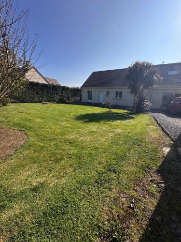 a yard with green grass and a house at Maison avec piscine chauffée, plages du débarquement in Crouay