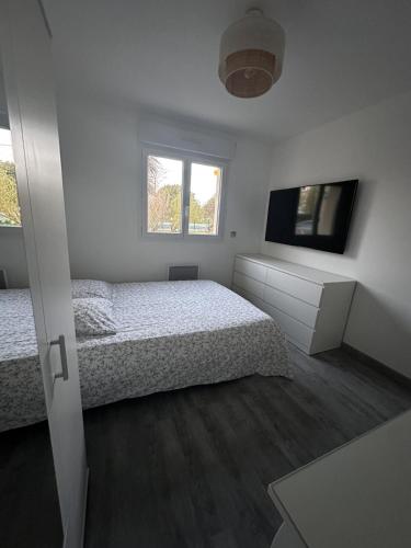 a white bedroom with a bed and a television at Maison avec piscine chauffée, plages du débarquement in Crouay