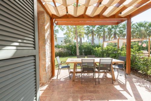 a patio with a table and chairs under a pergola at Mimosa Mansions in Bodrum City