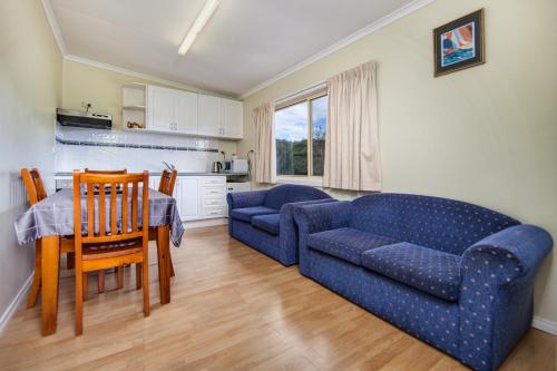 a living room with a blue couch and a table at Wintersun Gardens Motel in Bicheno