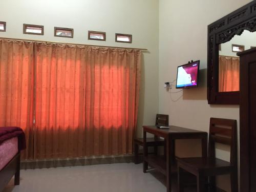 a room with a red curtain and a table and a television at Anugrah Borobudur in Borobudur