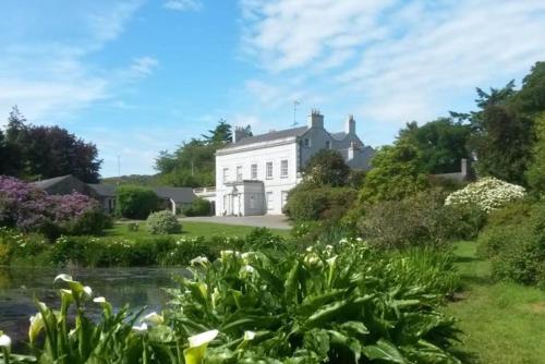 a white house with a pond in front of it at Kilmartin House - Georgian House on Private Estate and Farm in Greystones