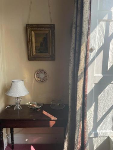 a table with a lamp and a picture on a wall at Kilmartin House - Georgian House on Private Estate and Farm in Greystones