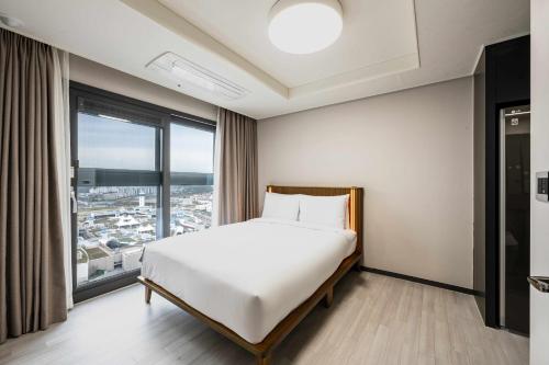 a bedroom with a bed and a large window at Odays Osiria Residence in Busan