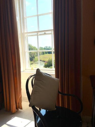 a chair with a pillow sitting in front of a window at Kilmartin House - Georgian House on Private Estate and Farm in Greystones