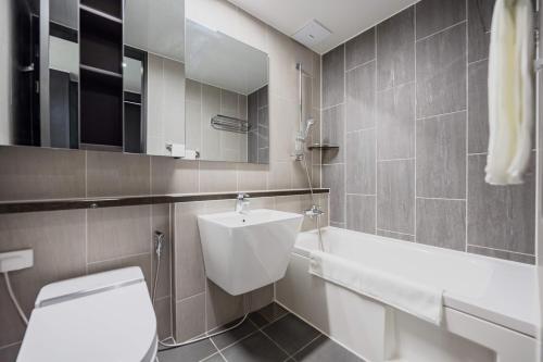 a bathroom with a toilet and a sink and a tub at Odays Osiria Residence in Busan