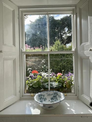 a bowl sitting on a window sill in front of a window with flowers at Kilmartin House - Georgian House on Private Estate and Farm in Greystones