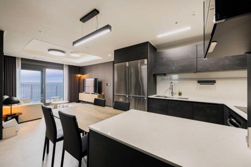 a kitchen with black cabinets and a table and chairs at Odays Osiria Residence in Busan