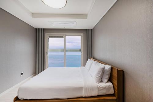 a bedroom with a bed with a large window at Odays Osiria Residence in Busan