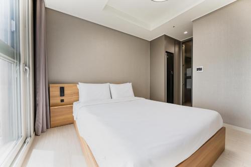 a bedroom with a large white bed and a window at Odays Osiria Residence in Busan