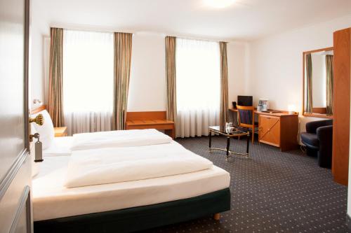 a hotel room with two beds and a desk at INA Hotel Royal in Cologne