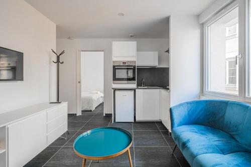un salon avec un canapé bleu et une table dans l'établissement R'Apparts T2 Bleu D'Alsace, à Grenoble
