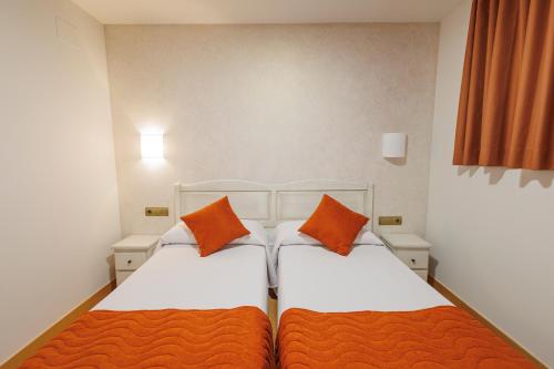two beds in a small room with orange pillows at Hotel Pattaya in Mocejón