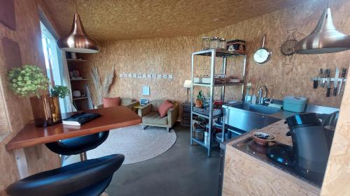 a kitchen with a sink and a counter with stools at Hut-Spot, comfortabel houten tuinhuis in Oud-Ade