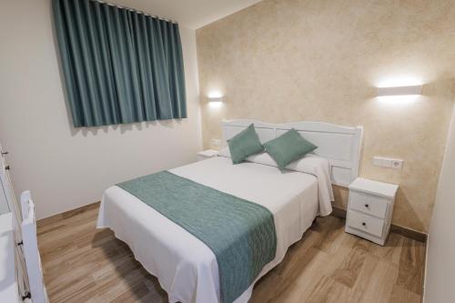 a bedroom with a large white bed with green pillows at Hotel Pattaya in Mocejón