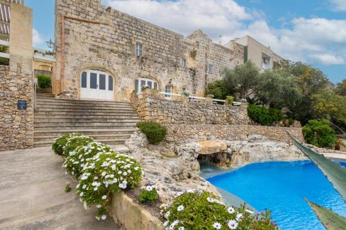 a stone building with stairs and a blue pool at Villeleynah Holiday Home in Munxar