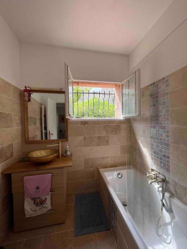 une salle de bain avec une baignoire, un lavabo et une fenêtre dans l'établissement Cannes hills villa with garden and parking, au Cannet