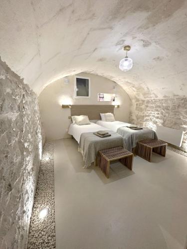 une chambre avec deux lits et un mur en pierre dans l'établissement Maison de Charme Centre Roquette, à Arles