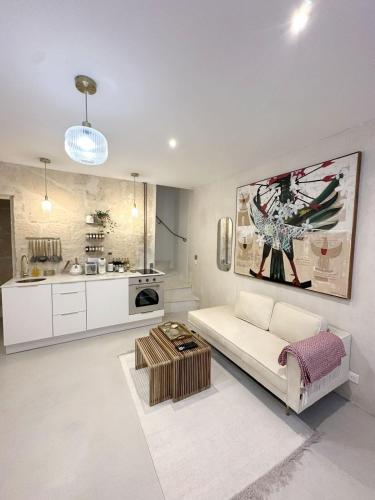 un salon avec un canapé blanc et une cuisine dans l'établissement Maison de Charme Centre Roquette, à Arles