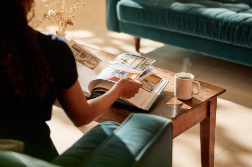 a woman reading a book on a coffee table at Constantine House in Tamworth